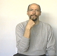 start of 'I tell him/her'. In a human picture, dominant hand's index finger extended and near mouth.